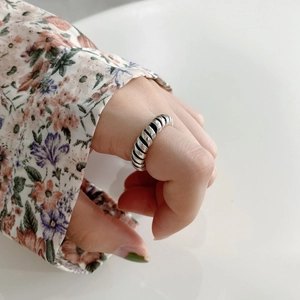 Minimalist 925 sterling silver twisted spiral ring worn on female hand with floral shirt