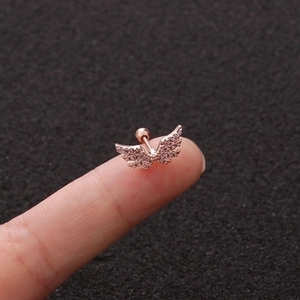 Rose gold angel wing cartilage stud with cubic zirconia in a macro view on finger