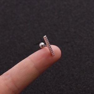 Silver rectangular zirconia ear stud in stainless steel shown on a fingertip for scale