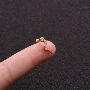 Creative gold snake ear stud with sparkling crystals shown on fingertip for size scale
