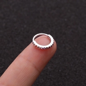 Kleiner silberner Ohrring mit Zirkonia-Steinen auf der Fingerspitze zur Größenansicht