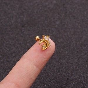 Macro detail of gold moon and butterfly helix stud earring with zircon inlay