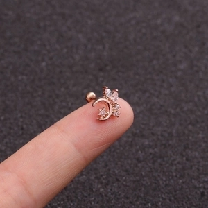 Detailed close-up of rose gold moon and leaf stud earring showing size on finger