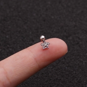 Petite silver flower cartilage stud with cubic zirconia stones shown on a fingertip