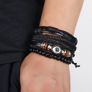 Multi-layer black leather bracelet set with woven bands and metal eye charm on wrist