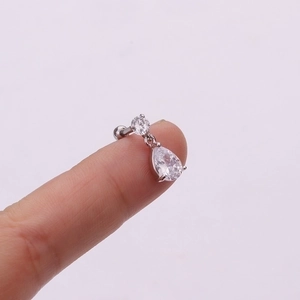 Detailed close-up of a silver flower drop earring with clear zircon crystals on a finger