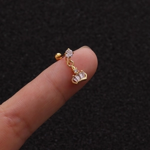 Macro shot of a golden crown cartilage stud earring featuring cubic zirconia on a fingertip