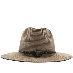 Detail of woven straw cowboy hat featuring a vintage bull skull emblem and wooden beads