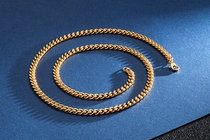 Detail of gold-plated stainless steel Cuban link chain with lobster clasp on blue background