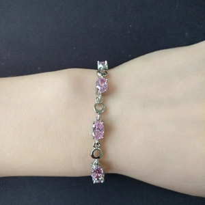 Detailed view of a silver rose gold plated bracelet with oval pink crystals on a wrist