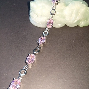 Detailed view of a silver bracelet featuring oval-shaped pink gemstones and sleek metal chain