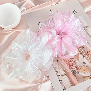 Iridescent pink and white organza scrunchies on satin fabric with an elegant backdrop