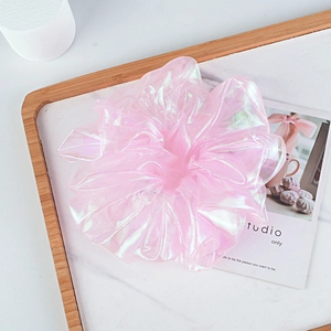 Detailed view of a pink iridescent organza hair scrunchie on a marble surface tray