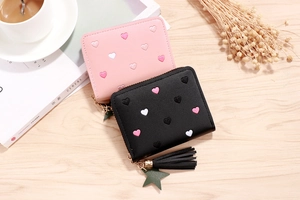 Pink and black PU leather wallets with heart embroidery and star tassel on wood table