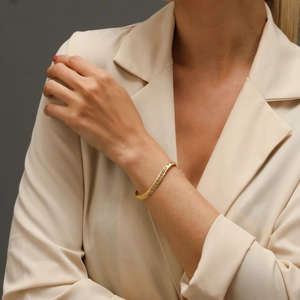 Nahaufnahme eines goldenen Gliederkettenarmbands getragen von einem Modell im Blazer