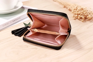 Detail of black PU leather wallet showing pink accordion compartments and gold zipper tassel