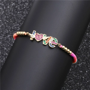 Adjustable woven LOVE bracelet with colorful zircons and gold plated metal on black stand