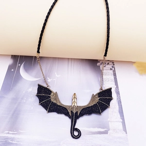 Close-up of vintage gold dragon pendant with detailed scales on black woven cord