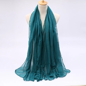 Detailed view of dark teal gauze scarf with natural crinkled texture on mannequin
