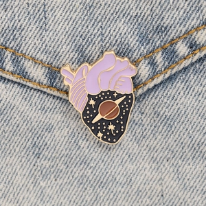 Detailed macro of a purple heart-shaped enamel pin on blue denim fabric background