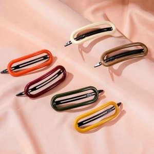 Detailed close-up of six colorful oval hollow resin hair clips on pink silk fabric