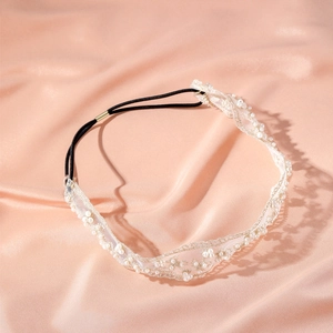 Détail macro du bandeau en dentelle élégant avec perles sur fond de soie rose doux