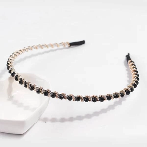Close-up of elegant gold metal headband featuring sparkling black faceted crystal beads