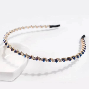 Detailed macro of crystal headband with deep blue beads and gold accents on white base