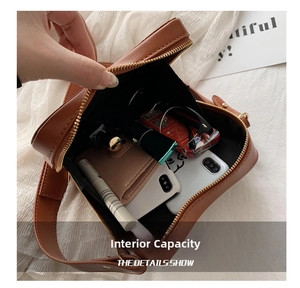 Dettaglio della capacità interna di una borsa a tracolla marrone con oggetti quotidiani