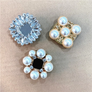 Three elegant vintage-style crystal and pearl phone grips on a rustic paper background