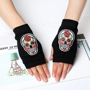Close-up of black knitted fingerless gloves featuring colorful sugar skull embroidery