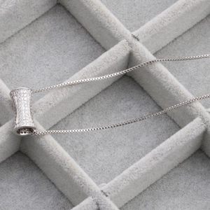 Silver micro-paved cubic zirconia cylinder pendant necklace on a velvet display tray