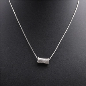 Close-up of silver micro-paved zircon cylinder pendant necklace on black mannequin