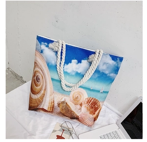 Detail of nautical tote bag featuring seashell prints and thick rope handles for beach trips
