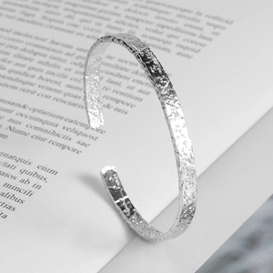 Minimalist silver cuff bracelet featuring an artistic hammered texture and open design