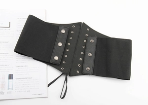 Detail of black elastic corset belt featuring metallic eyelets and snap buttons