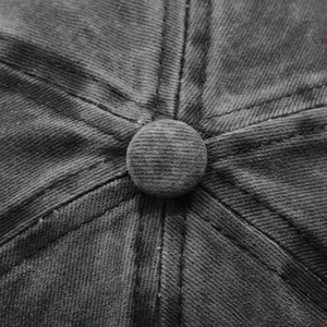 Close-up of a charcoal grey washed cotton baseball cap with stitch and top button detail