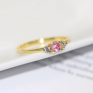 Elegant gold plated ring featuring a round pink zircon center stone and white side gems