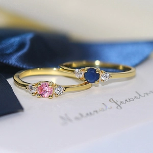 Minimalist gold plated wedding rings with pink and blue zircon stones on silk
