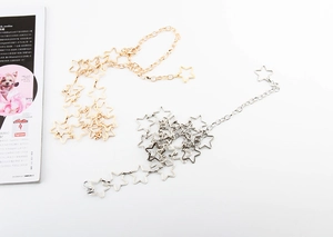 Detailed view of silver and gold star-shaped chain belts for women on white surface