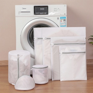 Set of multi-size mesh laundry bags for delicate clothes shown in front of a washing machine