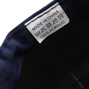 Detail view of the navy baseball cap showing 100% acrylic material and care label