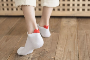 Detail of white low-cut cotton socks featuring a red heart heel tab on wooden background