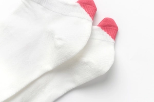 Close-up of white knit ankle socks with pink heel and toe details for women