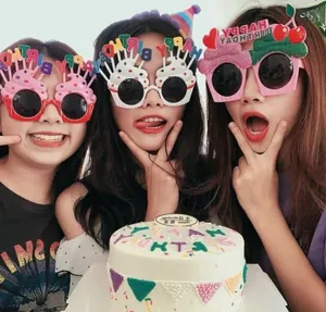 Three women wearing birthday party glasses shaped like ice cream and cupcakes