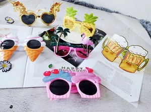 Close-up of assorted fun party sunglasses including flamingo and pineapple designs