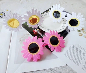 Detailed close-up of daisy shaped party sunglasses in white and pink color options
