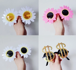 Close-up of four fun party sunglasses featuring daisy floral shapes and a dollar sign design