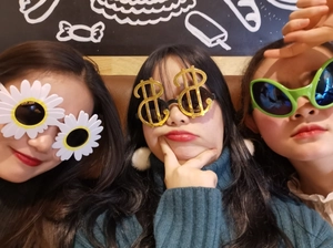 Close-up of three novelty party sunglasses featuring daisy, dollar sign, and green shapes
