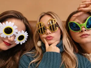 Close-up of three novelty party sunglasses featuring daisy, dollar sign, and green shapes